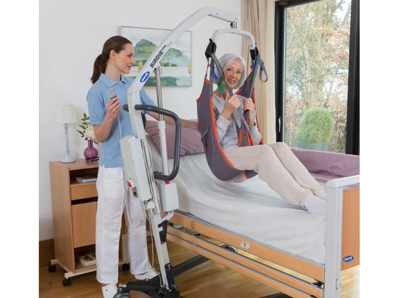 Pflegepersonal hebt ältere Frau mit Patientenlifter aus dem Bett